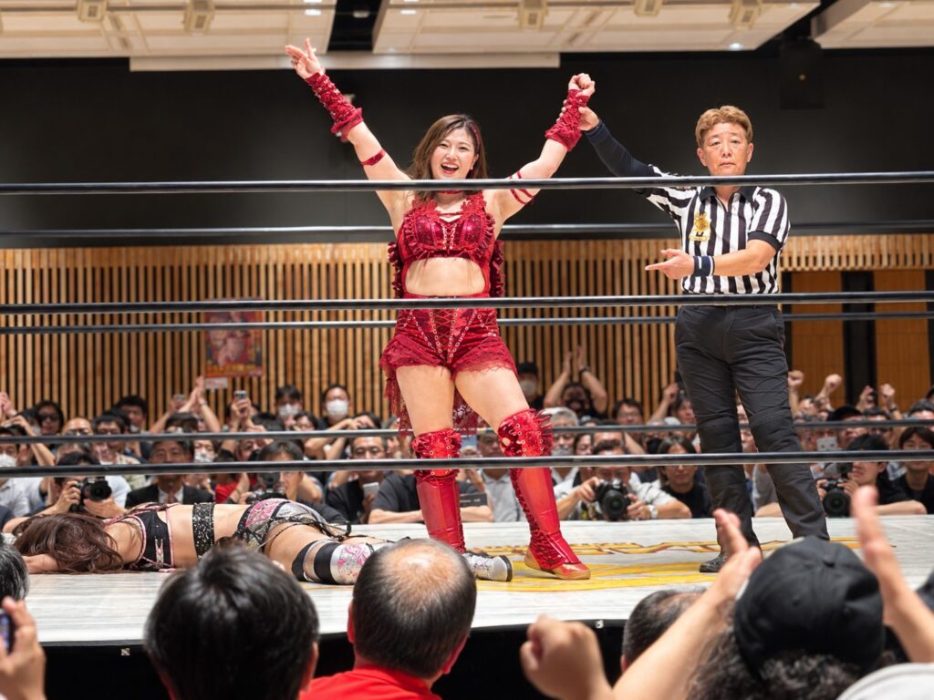 勝利しレフェリーに手を掲げられる女子プロレスラー