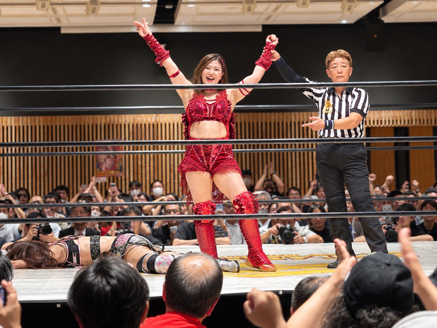 勝利し、レフェリーに手を掲げられる女子プロレスラー