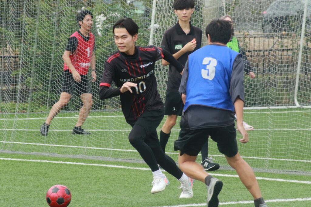 赤と黒のビブスの選手による試合中の攻防シーン