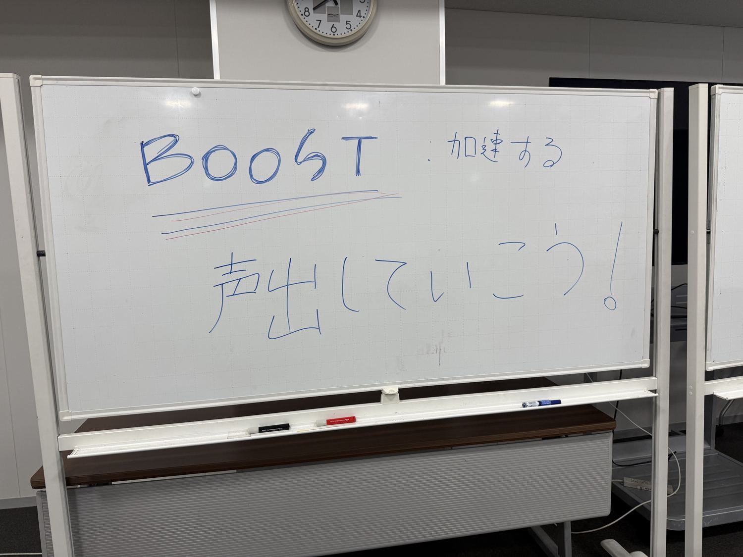 「BOOST 加速する」「声出していこう！」と書かれたホワイトボード